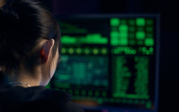 A security analyst monitoring code on dark screens